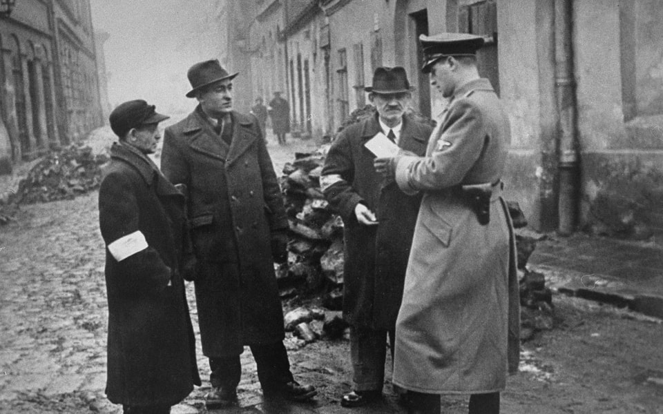 A German policeman checks the identification papers of Jews in the Krakow ghetto 1941