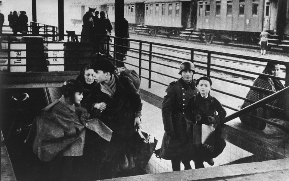 A Jewish family climbs the stairs to the train platform at the railway station during a deportation action from the Krakow ghetto 1941