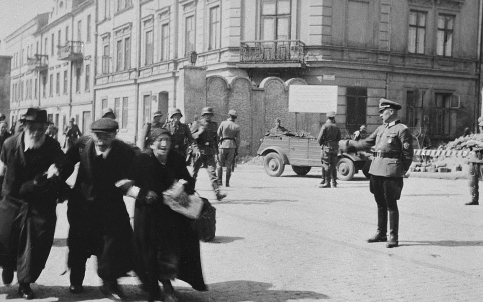 Three elderly Jews walk arm-in-arm through the streets of Krakow during the final liquidation action of the ghetto. march 1943