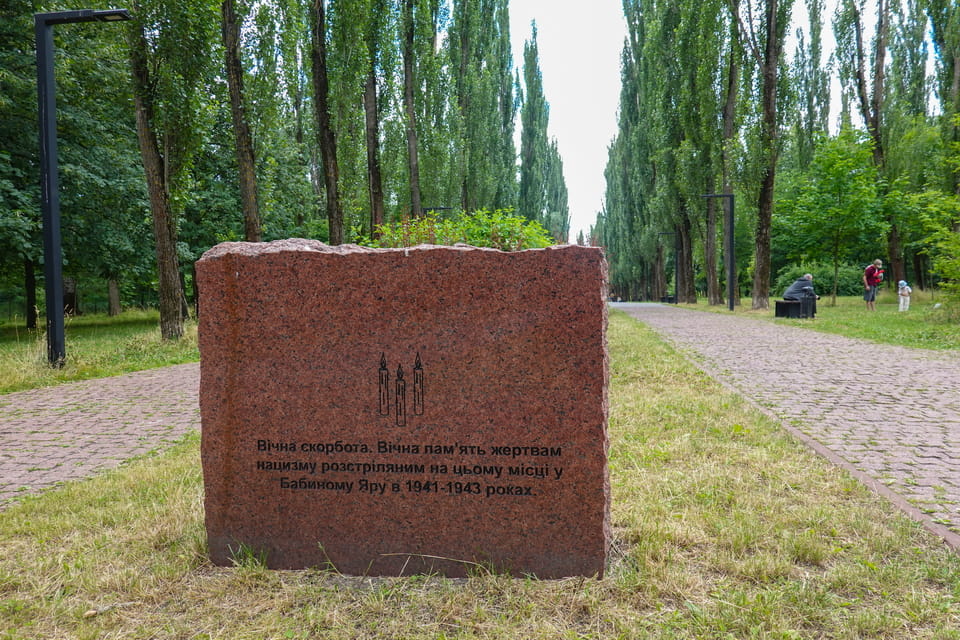 Memorial stone to mark the construction of Babi Yar Righteous Alley. Babyn Yar (Babi Yar) memorial park in Kyiv today — the main allée with national memorials, view toward Dorohozhychi metro station