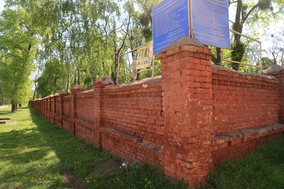 The original red-brick perimeter wall of Lukyanivske Orthodox Cemetery (built 1920s) still standing today — from behind this wall witnesses observed the Babi Yar executions in September 1941