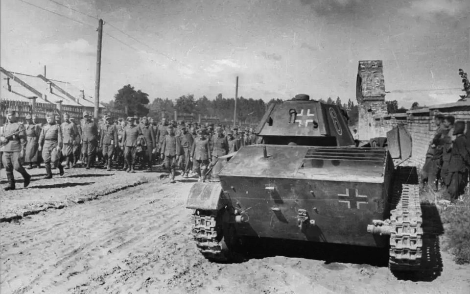 Soviet guards escorting a column of German POWs along the walls of the Lukyanivske Jewish Cemetery, Kyiv, 16 August 1944 — main entrance to the cemetery visible on the right