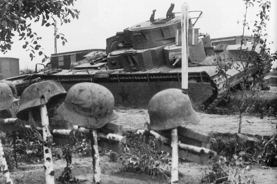 The graves of German soldiers against the backdrop of a Soviet heavy tank T-35, knocked out on the route Verba village - Ptichye village (Ukraine)