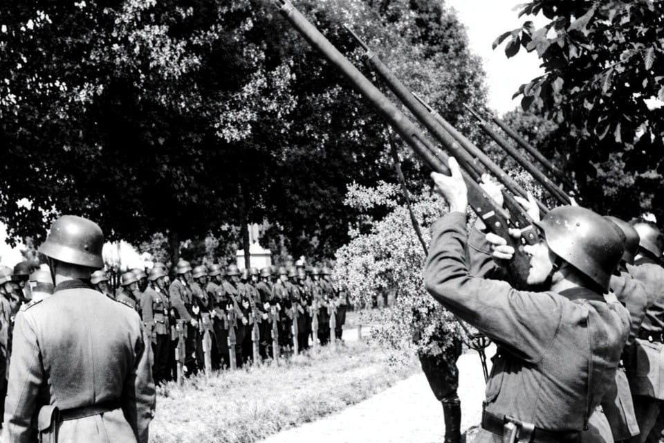 German soldiers salute with rifles at a military funeral
