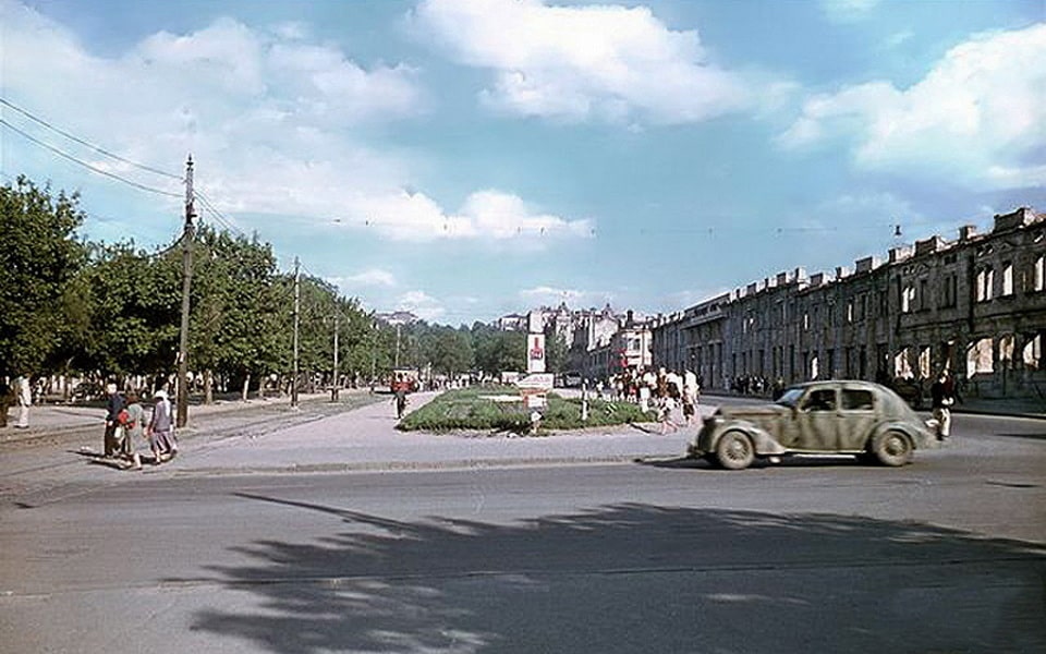 Rare colour photograph of Dnipropetrovsk under German occupation — Nazi banner visible in the background, destroyed buildings, German vehicle on the main street, 1941–1943