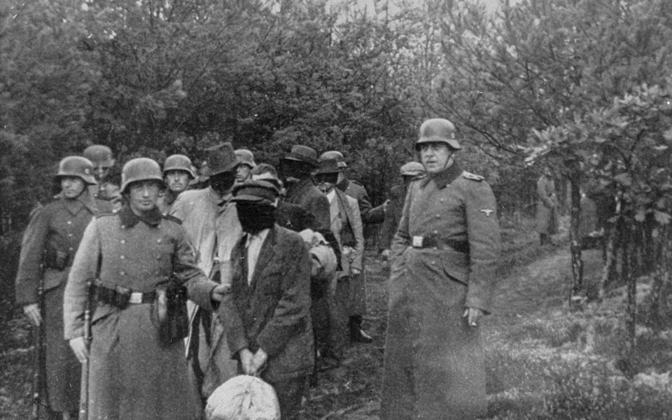 SS personnel lead a group of blindfolded Polish prisoners to an execution site in the Palmiry forest near Warsaw. These civilians had been held in the Palmiry and Mokotow prisons in Warsaw_