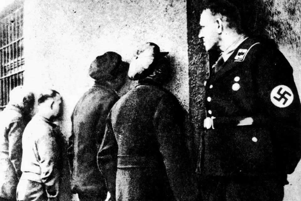 1942. Jews and Poles stand facing the wall in a torture chamber of the SD in the Szuchr Allee, guarded by a Gestapo member