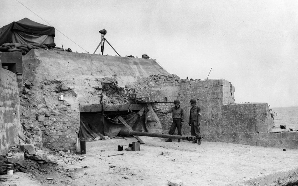 A German 88-mm gun projects from the Normandy beachhead. Omaha Beach, France