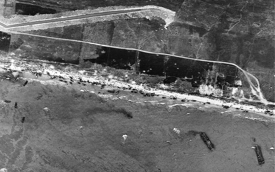A fascinating aerial view of the 1st Division side of Omaha beach on D-Day. The antitank ditch is quite visible, as are vehicles and soldiers on the beach