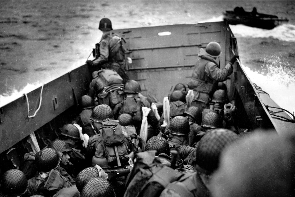 A waterlogged boat section heads toward Easy Red beach. An officer, presumably the commander, is at the front left, peering over the ramp
