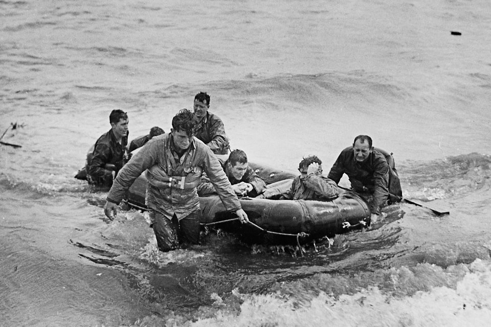 Soldiers make for the shore in a rubber life raft after their LCVP has been sunk several hundred meters offshore of Omaha Beach.