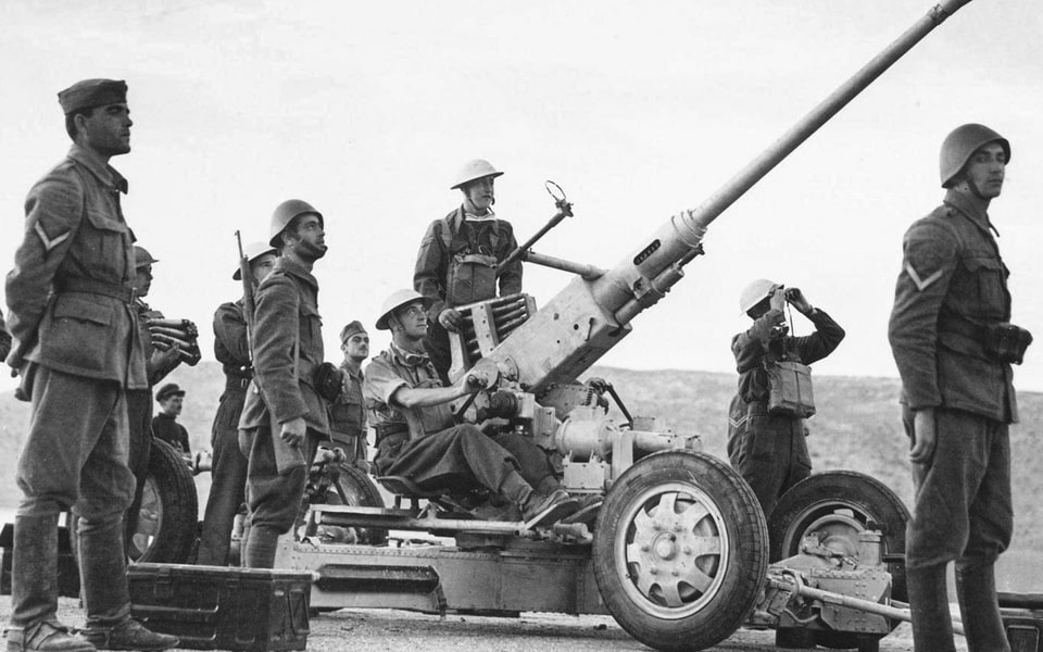 A British 40mm Bofors automatic anti-aircraft gun crew at a position in Greece. Greek soldiers stand next to the anti-aircraft gun position