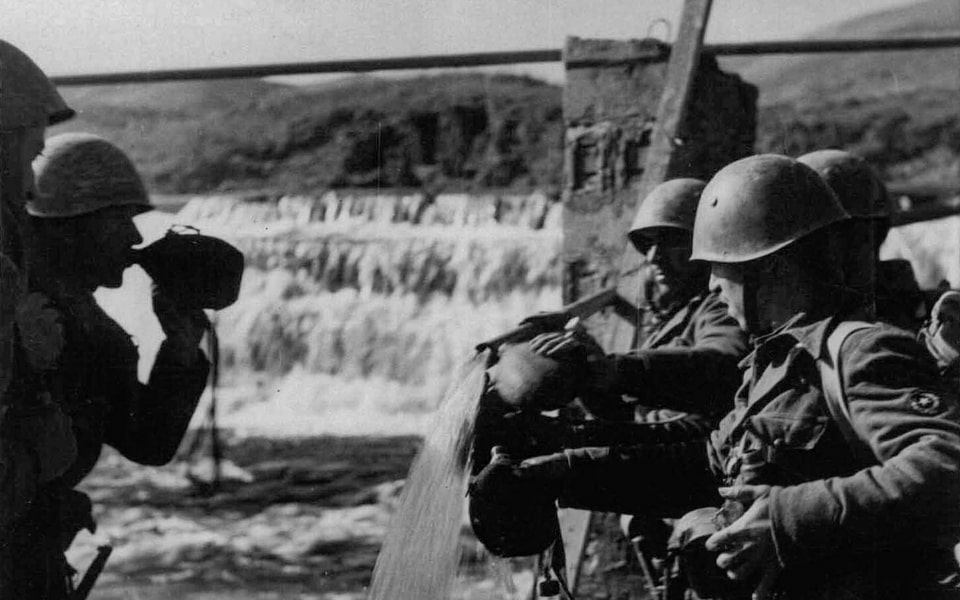 Italian soldiers fill their water bottles at a waterfall in Albania