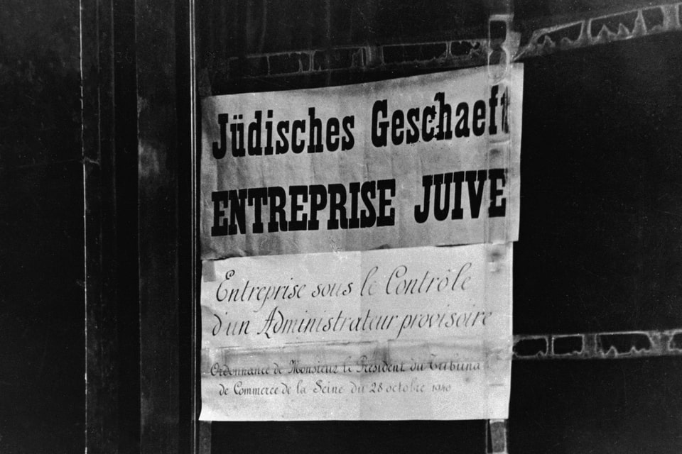 A sign in German and French on a shop Jewish business