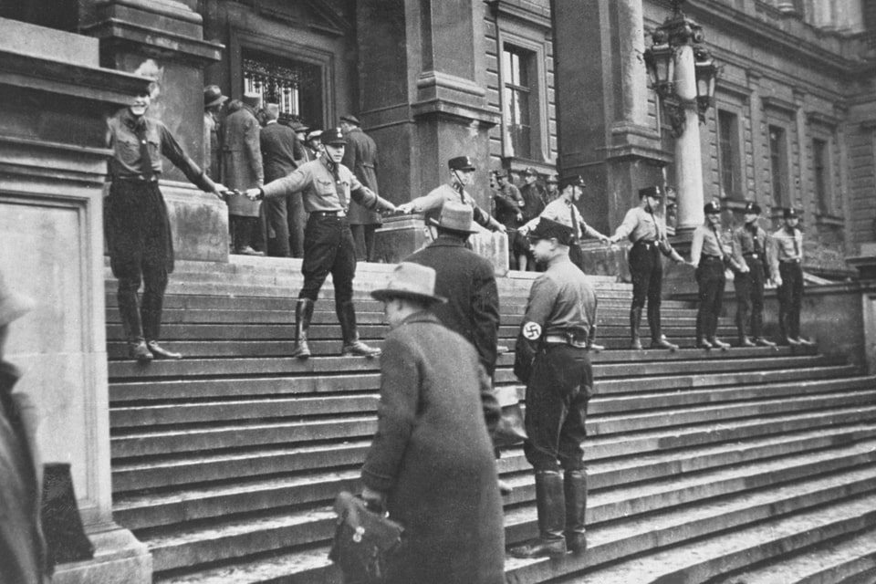 A group of SA hold hands on the steps of the University of Vienna in an attempt to prevent Jews from entering the building. The action led to a day of student rioting, which had to be suppressed by police_