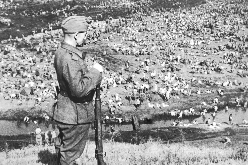 A German soldier and an open-air prison camps behind the frontline