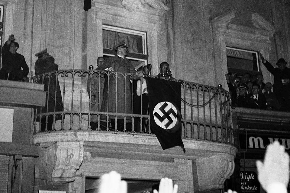 Adolf Hitler standing on the balcony of the town hall in his hometown of Linz