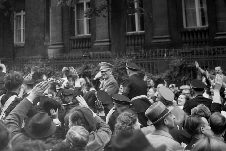 Adolf Hitler greets the crowd in front of the Italian embassy in Vienna